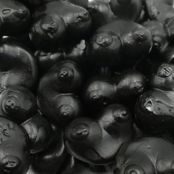 Black licorice candies with glossy finish in playful shapes, bulk confectionery close-up.