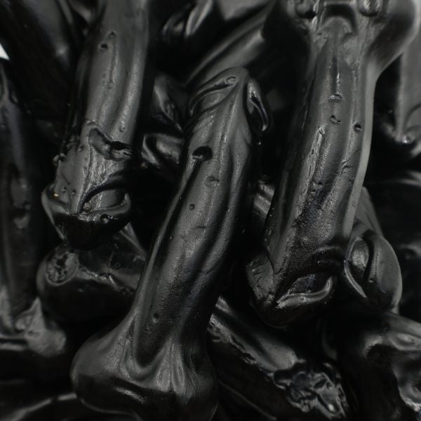 Close-up of black licorice drop candies shaped like bones, glossy finish